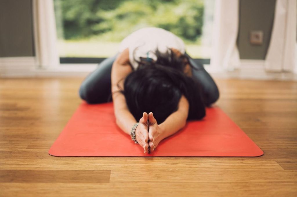 Yin Yoga for Finding Zen, Calm and Balance 4 Woman laying down on yoga mat with hands together above her head.